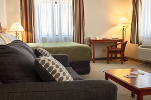 A hotel room with a bed, a sofa, a desk, and a chair. - Quality Inn Delta Gateway to Rocky Mountains (Delta)