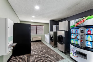 Una cucina moderna con frigorifero, forno a microonde e distributore automatico di Mountain Dew e altre bevande.