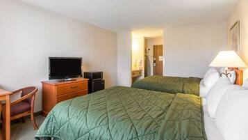 Habitación de hotel con dos camas, un escritorio con televisor y una silla.