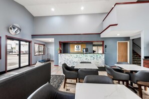 A modern hotel lobby with a reception desk, seating area, and a view of the outside.