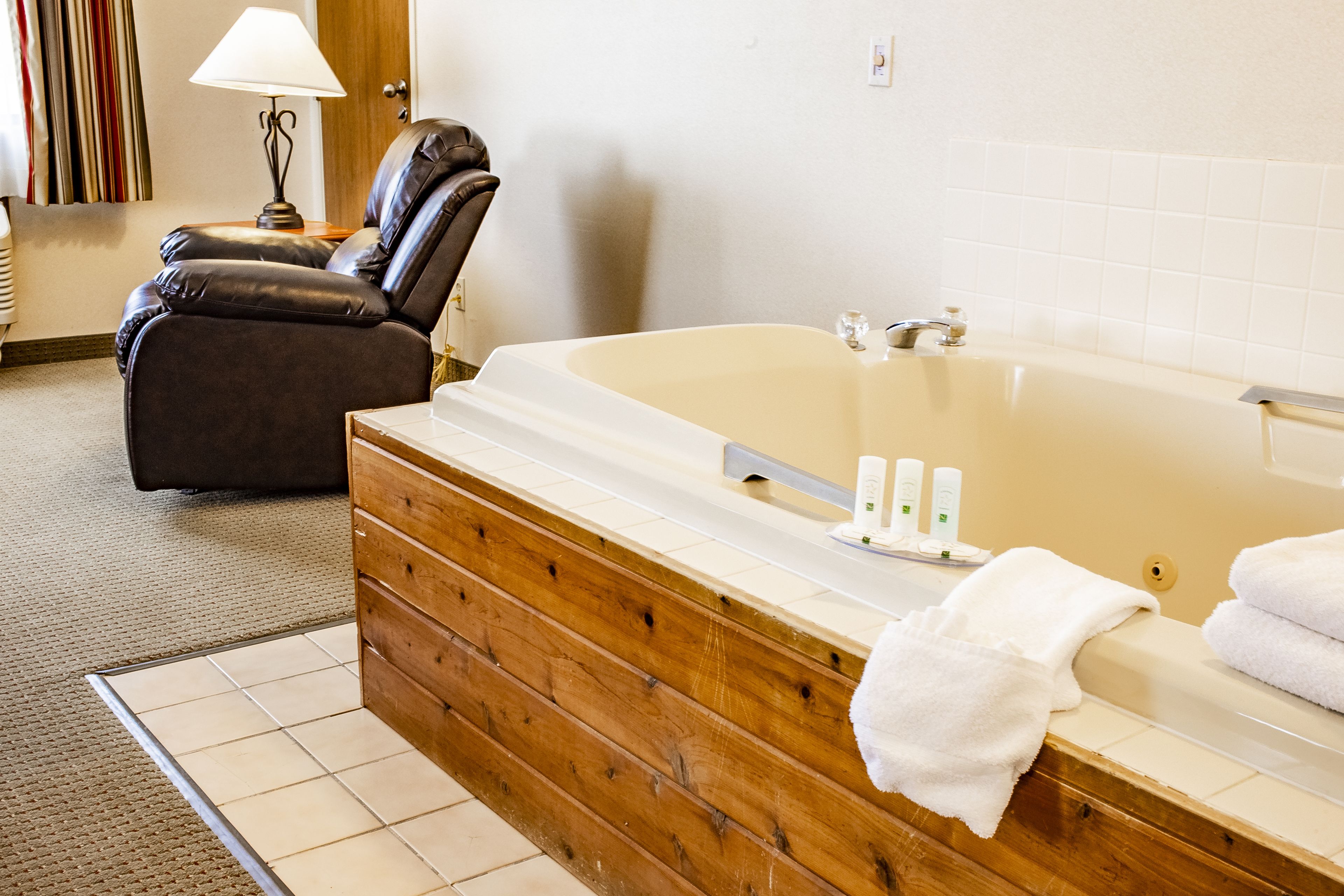 A bathroom with a wooden vanity, a large bathtub, and a massage chair.