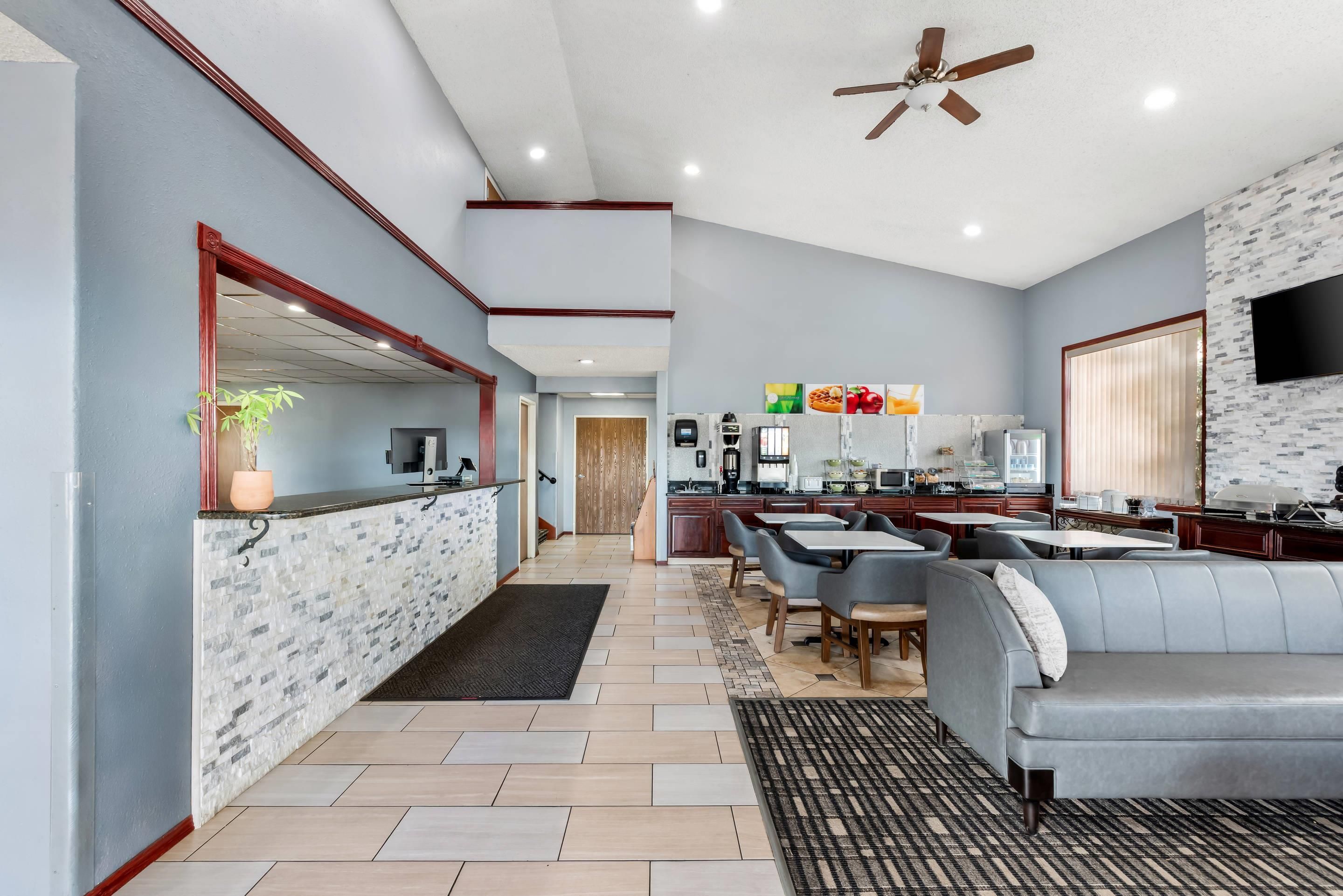 Una cocina moderna con una isla central, un área de comedor con un sofá y sillas, y un ventilador de techo.