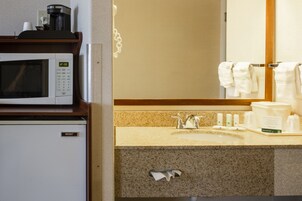 Un baño de hotel con microondas, lavamanos y artículos de aseo.