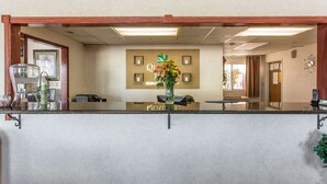 A reception area with a reception desk, a framed picture on the wall, and a vase with flowers.