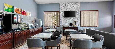 A restaurant with a counter, seating area, and a television.