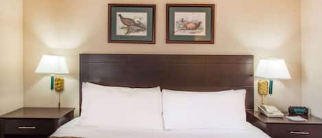 Ein Hotelzimmer mit einem großen Bett, zwei Nachttischen, einem Holzkopfteil und zwei gerahmten Bildern an der Wand.