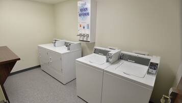 A laundry room with two white washing machines, a sink, and a soap dispenser.