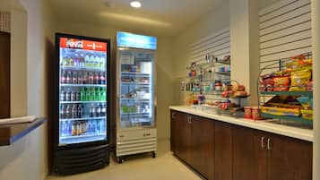 Un área de venta con un refrigerador de Coca-Cola y una nevera llena de bebidas y aperitivos.
