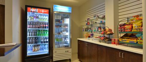 Un área de venta con un refrigerador de Coca-Cola y una nevera llena de bebidas y aperitivos.