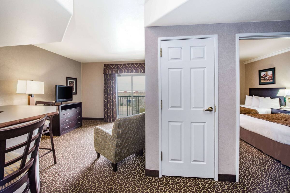 A hotel room with a desk, chair, television, and a bed.