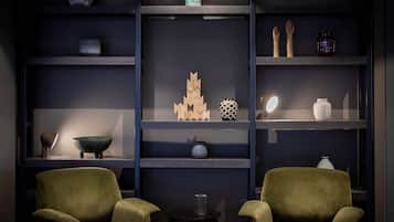 Un soggiorno moderno con due poltrone verdi, un tavolino da caffè e una libreria con oggetti decorativi.