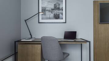 Un espacio de oficina moderno con un escritorio, una silla, una computadora portátil y una fotografía enmarcada de un paisaje urbano en la pared.