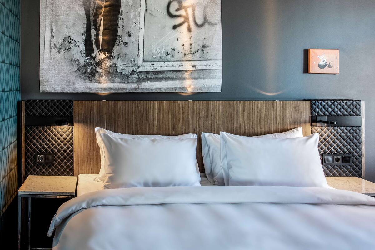 Una cama bien hecha con sábanas blancas en una habitación de hotel moderna.