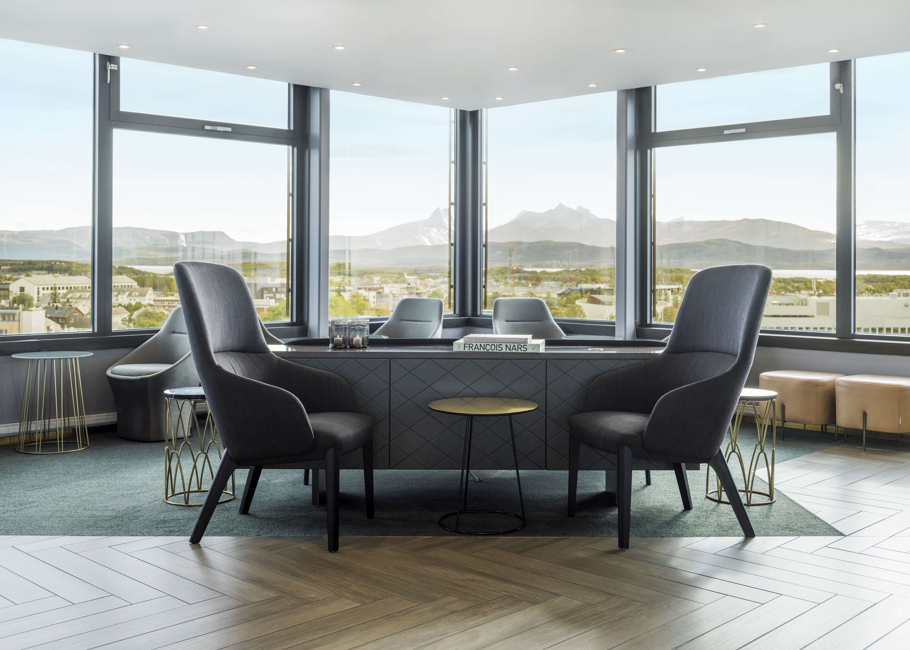 A modern meeting room with a large table, four chairs, and a view of a cityscape through large windows.