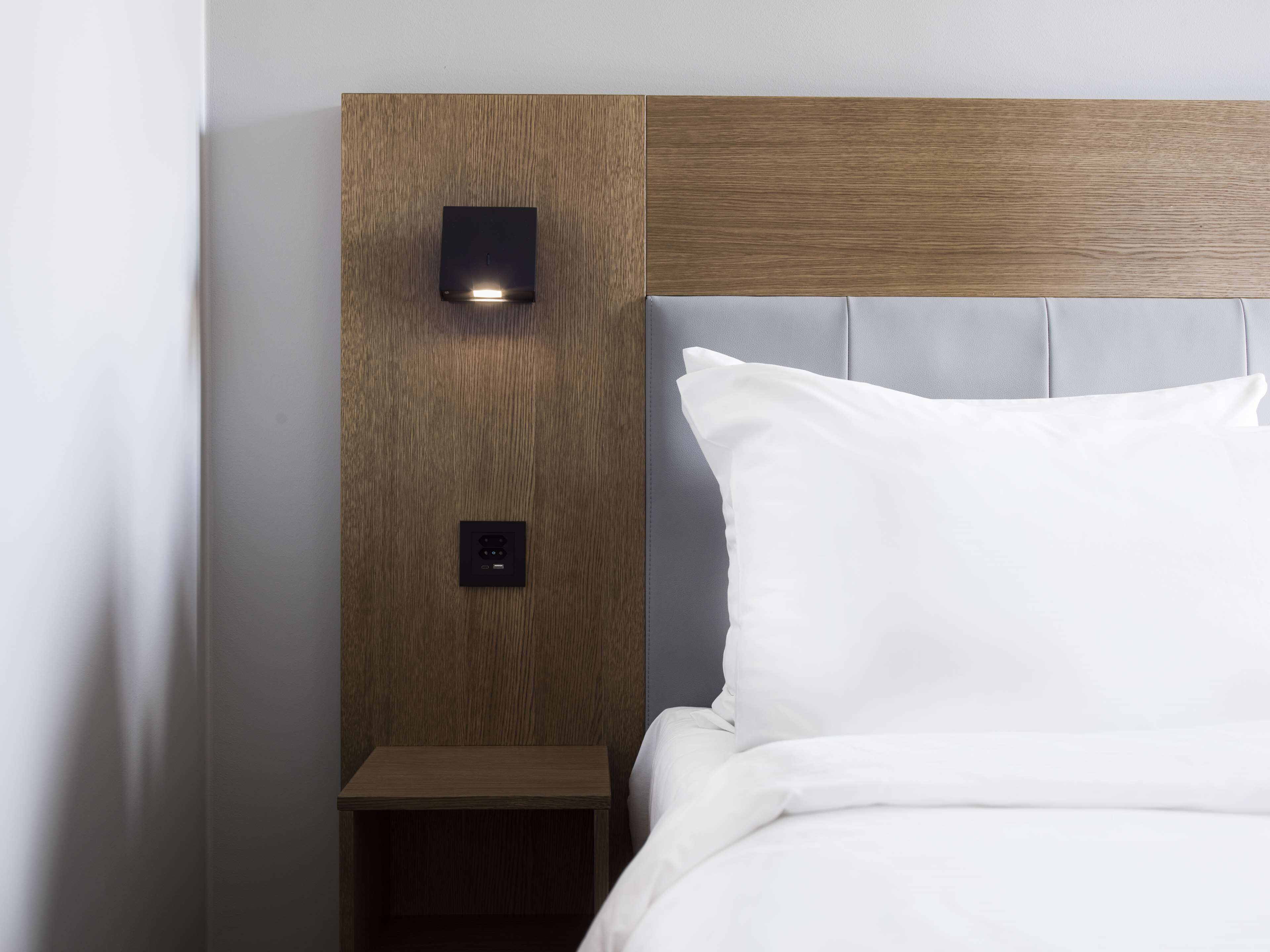 Una cama bien hecha con sábanas blancas y cabecera de madera.