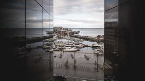 A marina with boats docked, a pier extending into the water, and buildings in the background.
