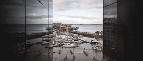 A marina with boats docked, a pier extending into the water, and buildings in the background.