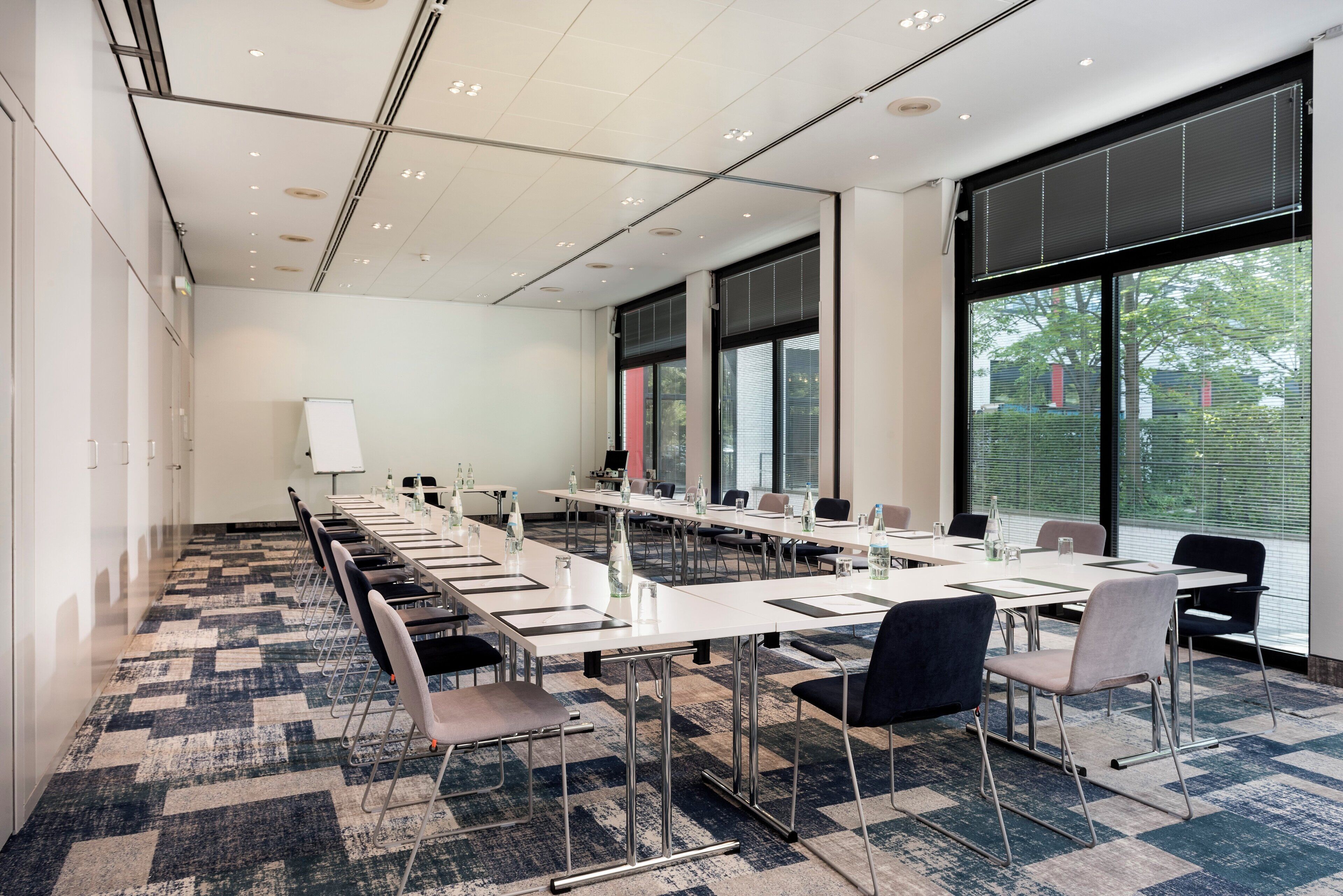 A conference room with long tables, chairs, and a whiteboard.