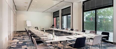 A conference room with long tables, chairs, and a whiteboard.
