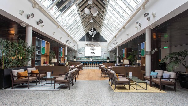 A spacious lobby with a high ceiling, a central bar area, and seating arrangements. - Holiday Inn Berlin City West by IHG (Berlin)