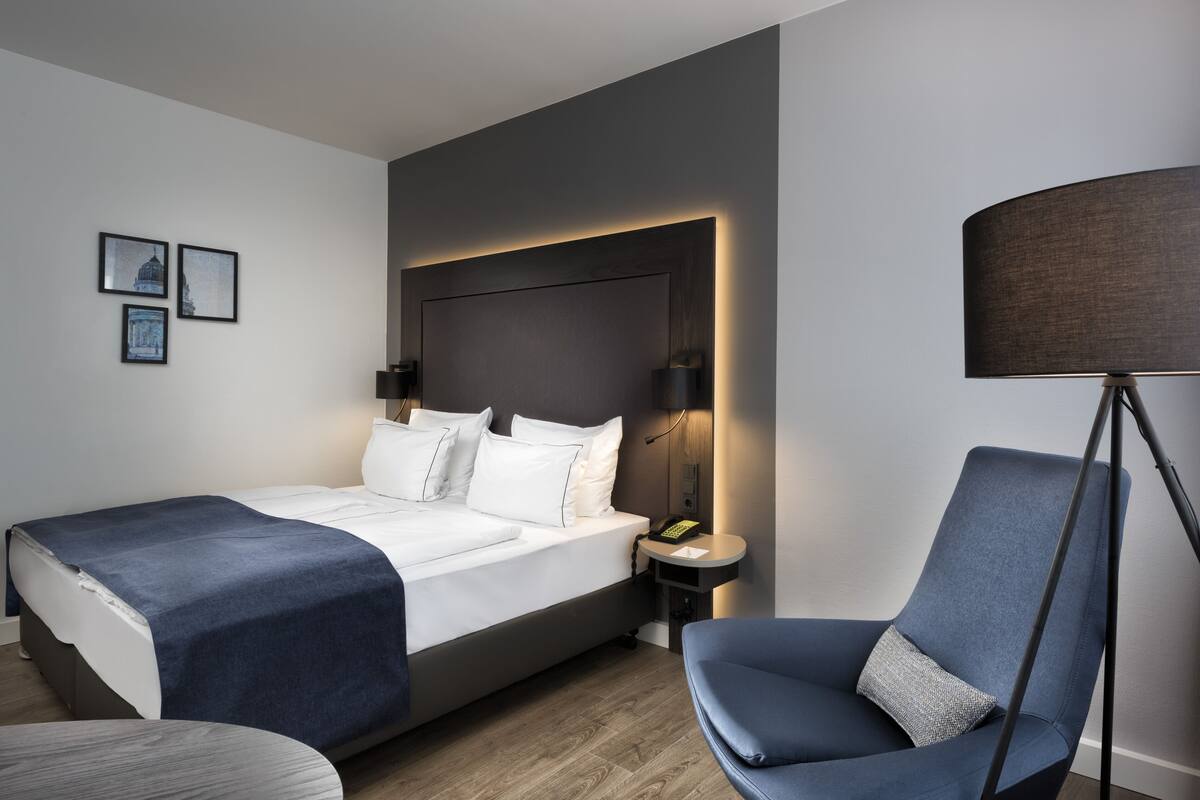 Una habitación de hotel moderna con una cama grande, lámparas de noche, un escritorio y una silla.