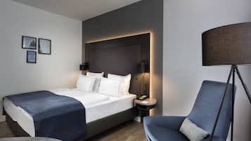 A modern hotel room with a large bed, bedside lamps, a desk, and a chair.