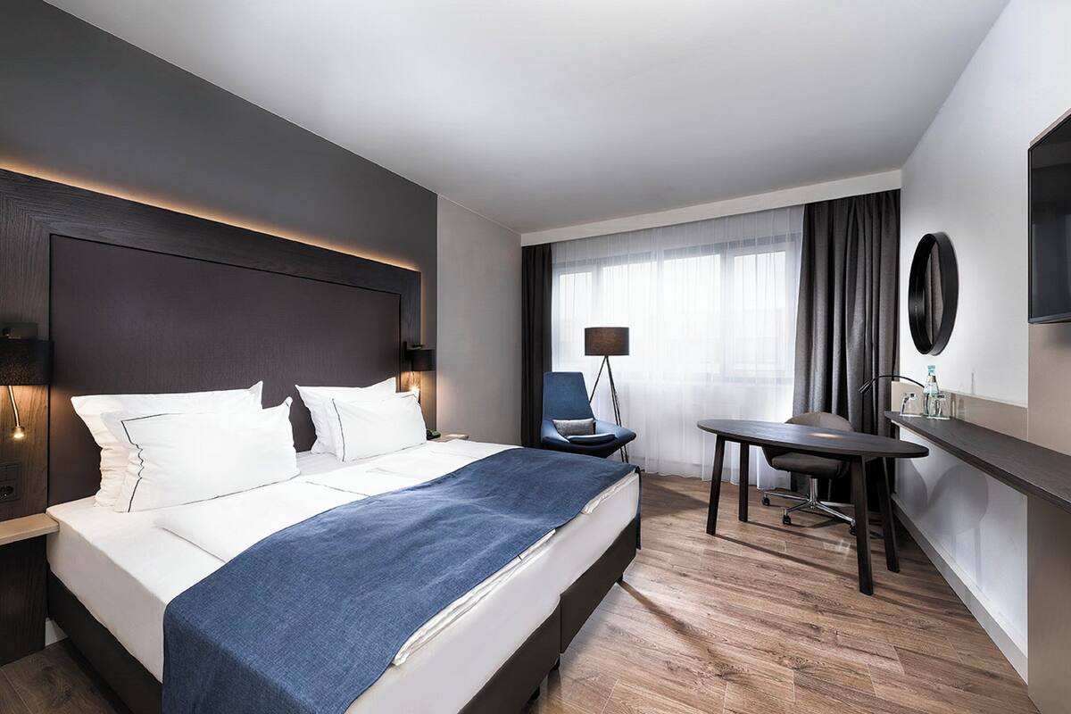 Una habitación de hotel moderna con una cama grande, un escritorio y una silla.