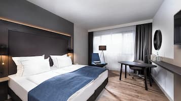 Een moderne hotelkamer met een groot bed, een bureau en een stoel.