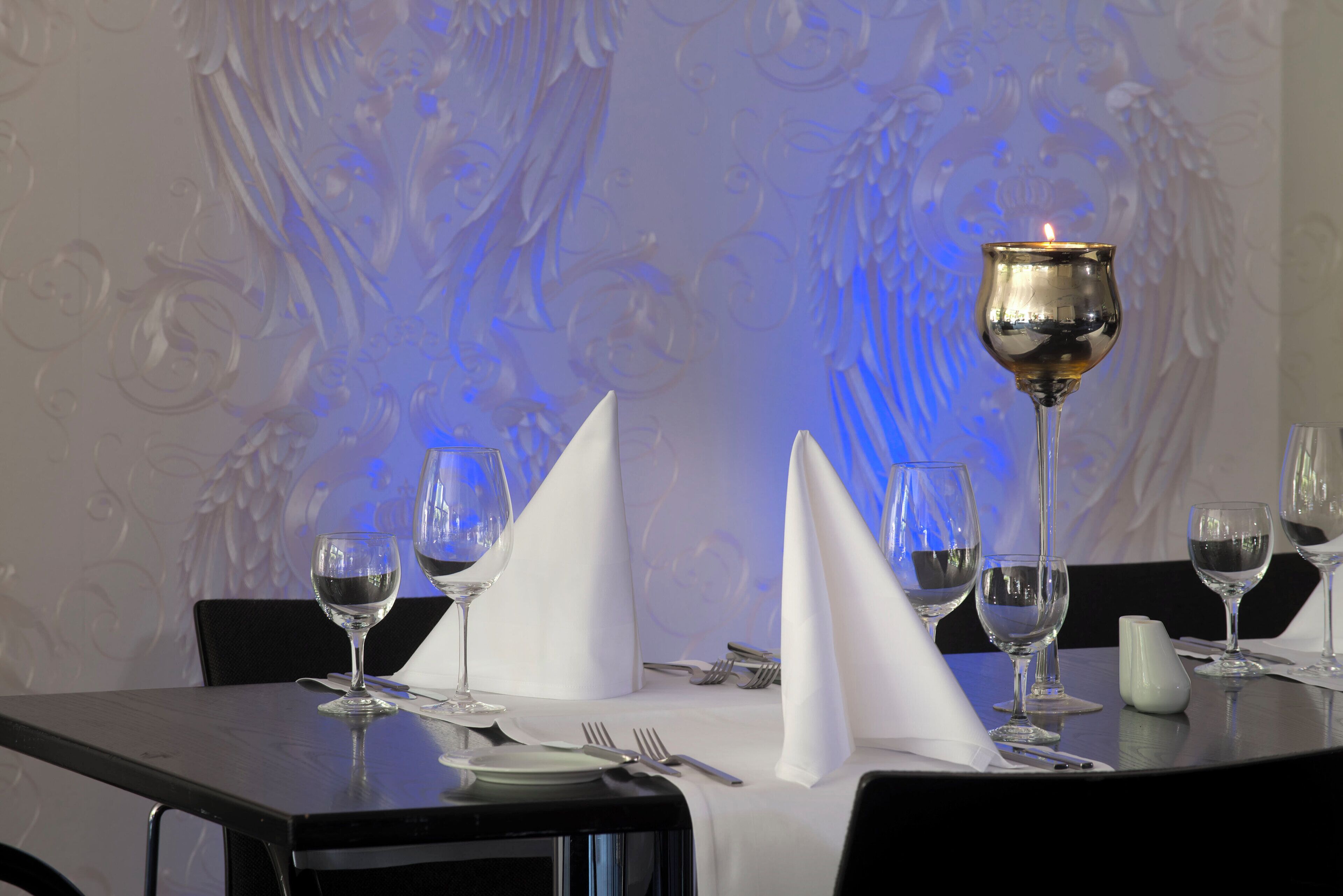 A dining table set with wine glasses, a candle, and a white napkin.