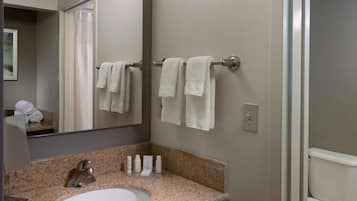 Un baño con lavamanos de encimera de granito, un espejo y un perchero para toallas.