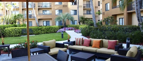 An outdoor patio area with wicker furniture, a table, and a large umbrella.