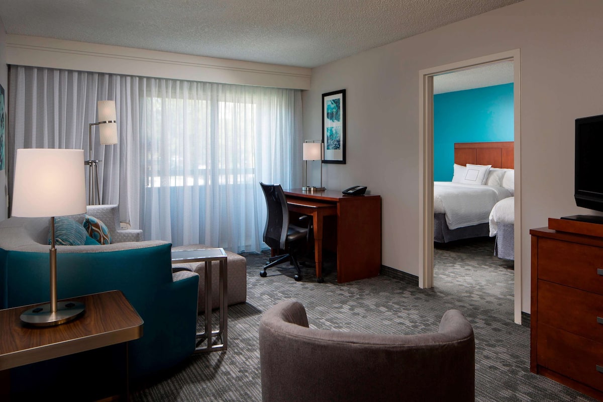 Une chambre d’hôtel équipée d’un lit, d’un bureau, d’une chaise, d’un canapé, d’une télévision et d’une lampe.