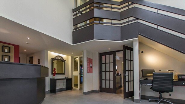 A modern office space with a reception desk, a computer, and a staircase leading to an upper level. - Comfort Inn Val-d Or (Val-d'Or)