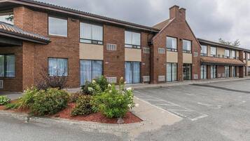 A row of brick buildings with large windows and a parking lot in front.