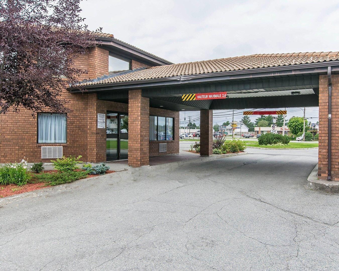 A gas station with a brick building, a covered entrance, and a sign indicating it is a 24-hour service.