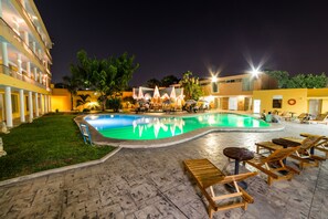 A swimming pool with lounge chairs and umbrellas, surrounded by a building with multiple floors and balconies. - Hotel Maria del Carmen Merida (Mérida)