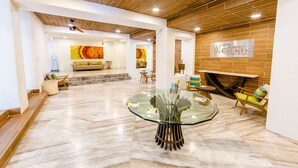 A modern lobby with a glass table, wooden ceiling, and a sign for Hotel María del Carmen Resort Maya. - Hotel Maria del Carmen Merida (Mérida)