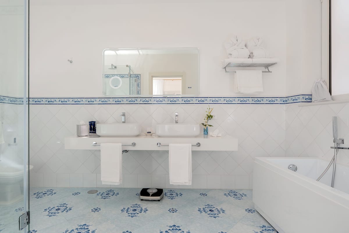 A bathroom with two sinks, a mirror, and a bathtub.