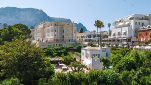 A hotel with a courtyard, multiple balconies, and a mountainous backdrop.