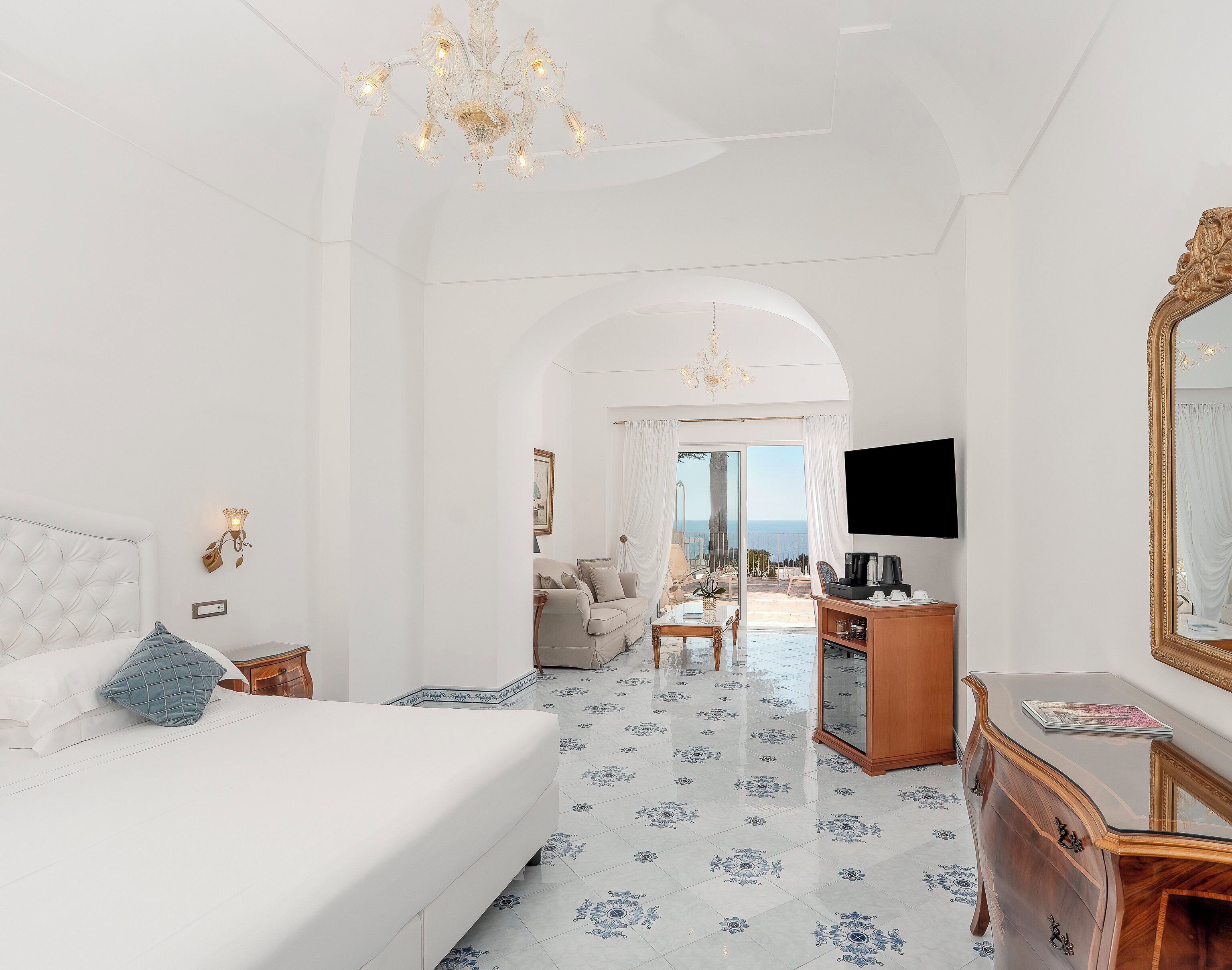 A spacious bedroom with a large bed, a desk, and a view of the sea.