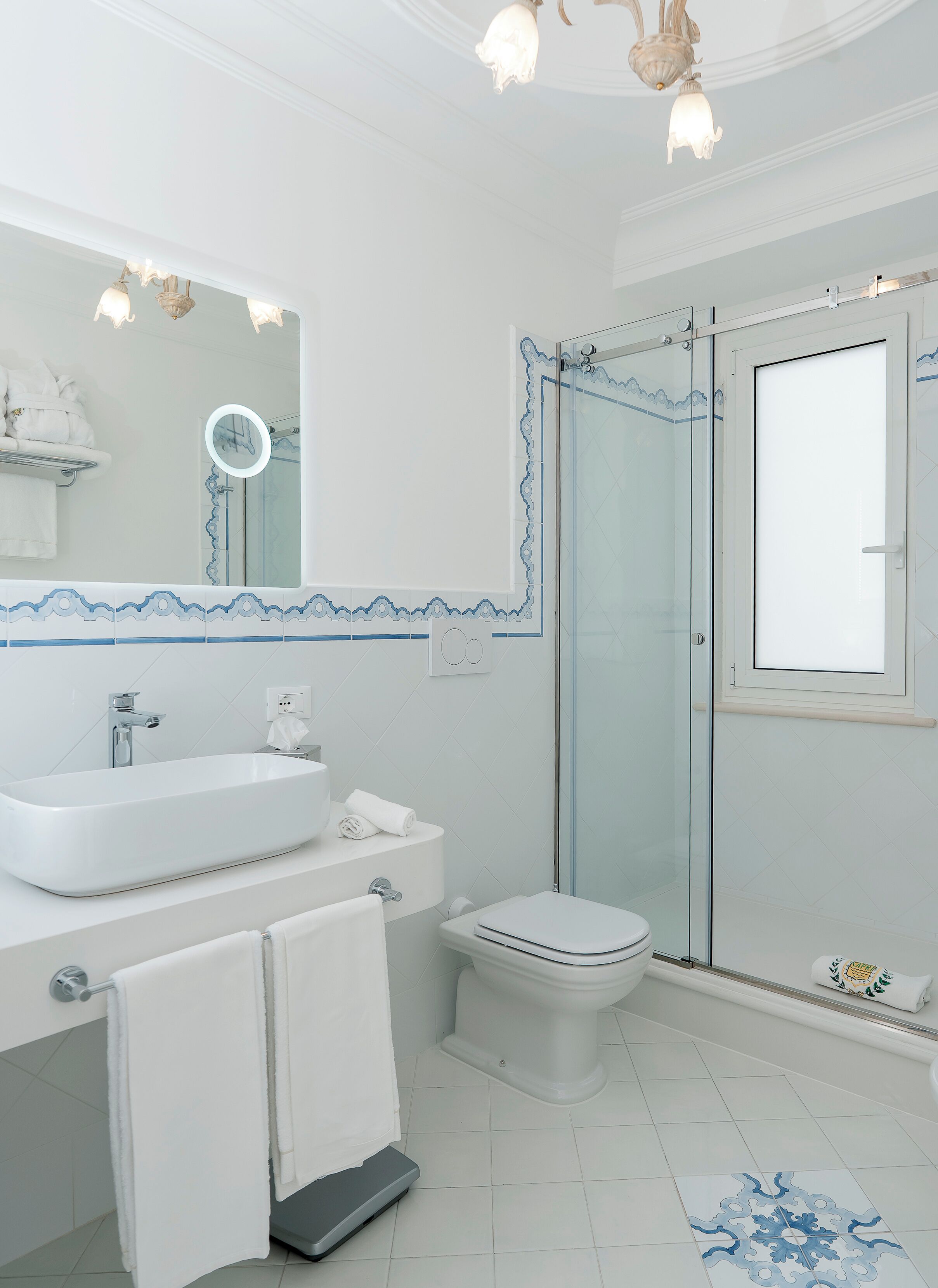 A modern bathroom with a large sink, toilet, and glass shower enclosure.