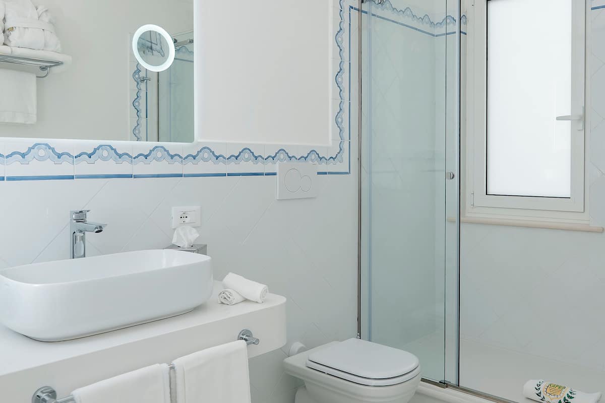 A modern bathroom with a large sink, toilet, and glass shower enclosure.