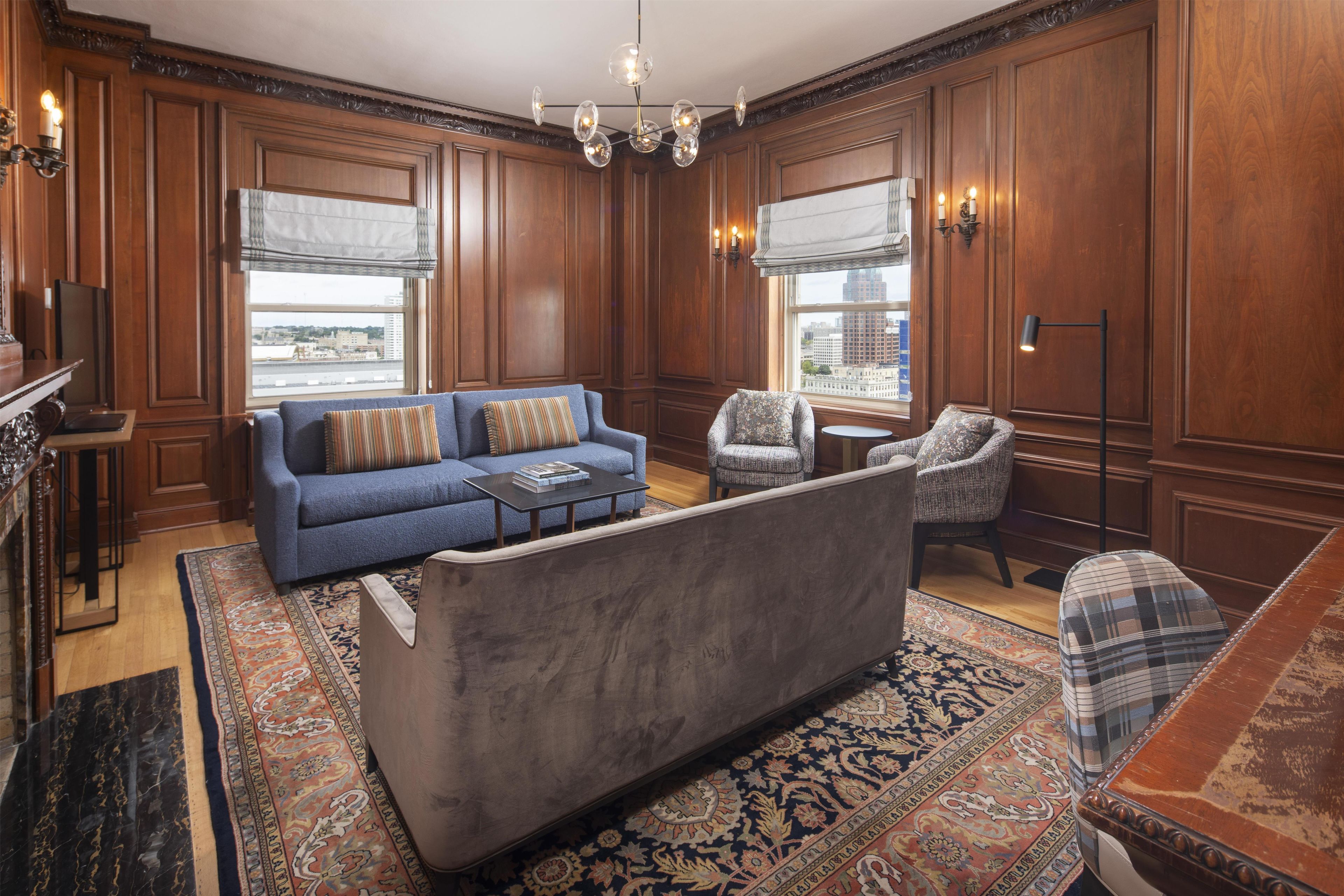 A spacious living room with a blue sofa, a patterned armchair, a coffee table, and a floor lamp.