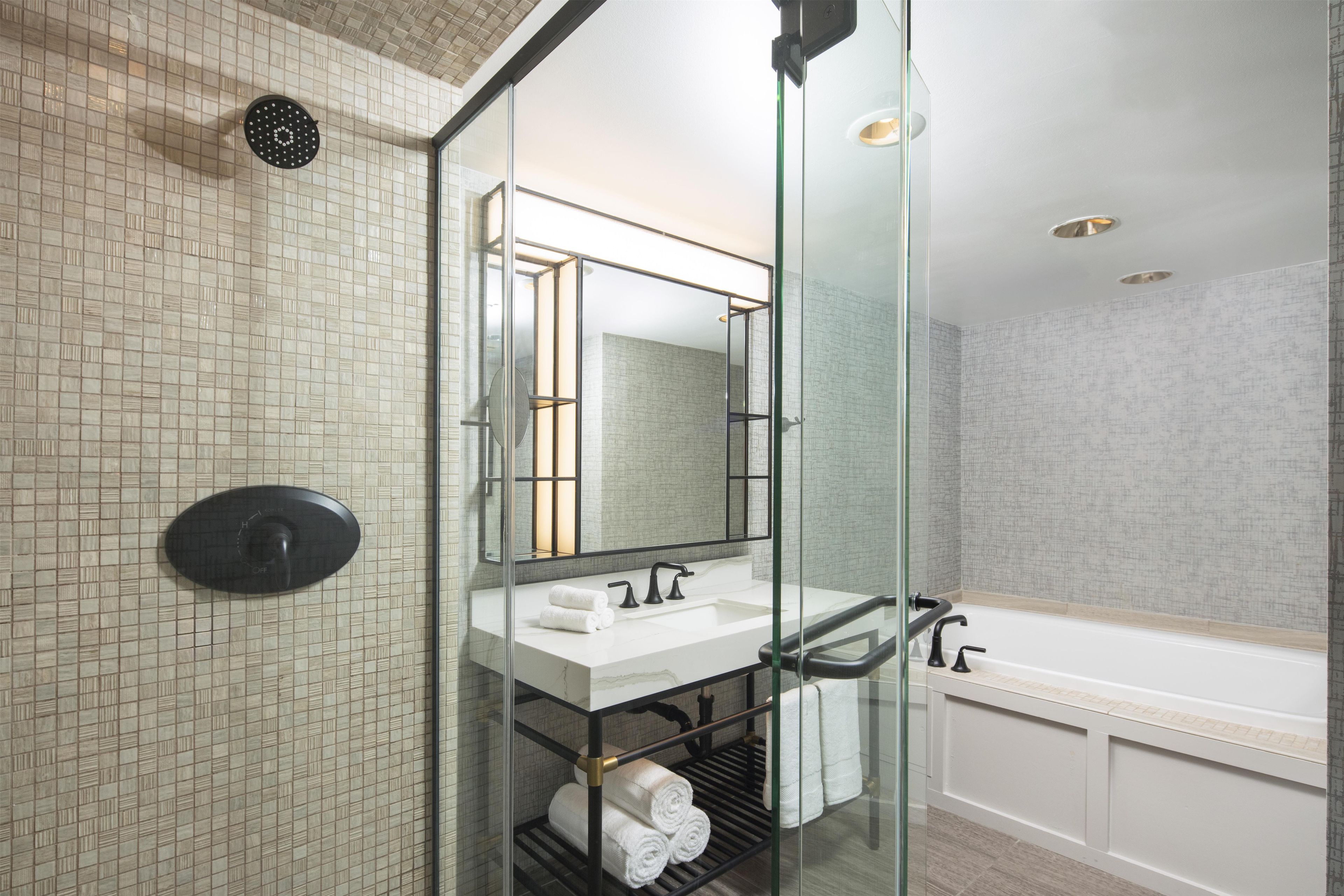 Ein modernes Badezimmer mit einer Duschkabine, einem weißen Waschbecken mit Spiegel und einer Badewanne.