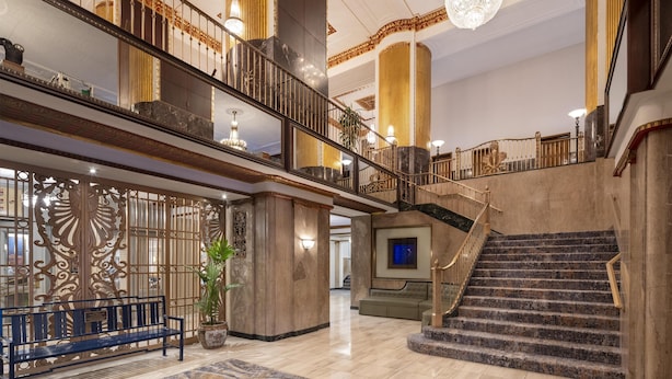 Eine großzügige Lobby mit einer Marmortreppe, einer Bank und einer Wandverkleidung.