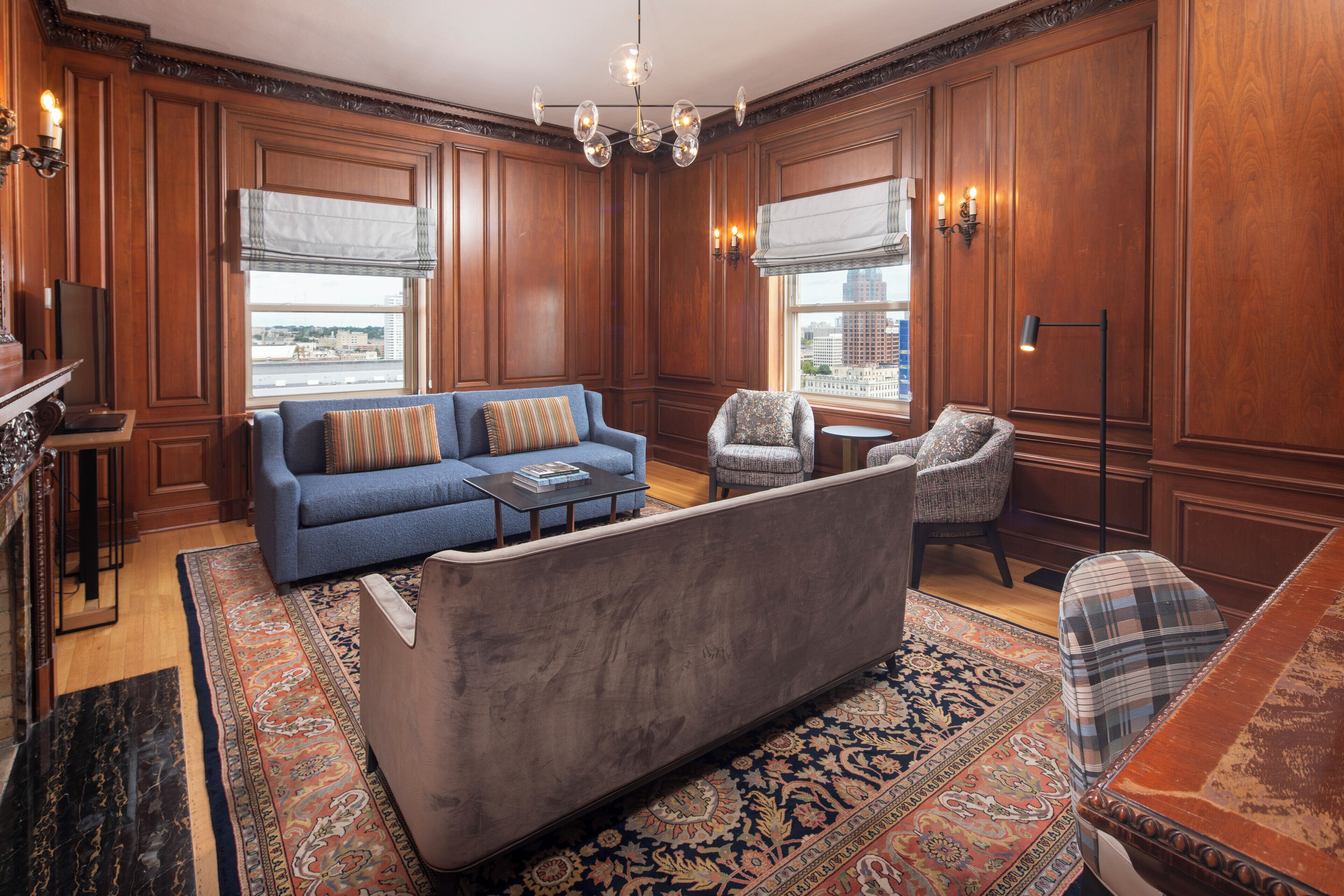 A room with a blue sofa, a patterned armchair, a small round table, and a floor lamp.
