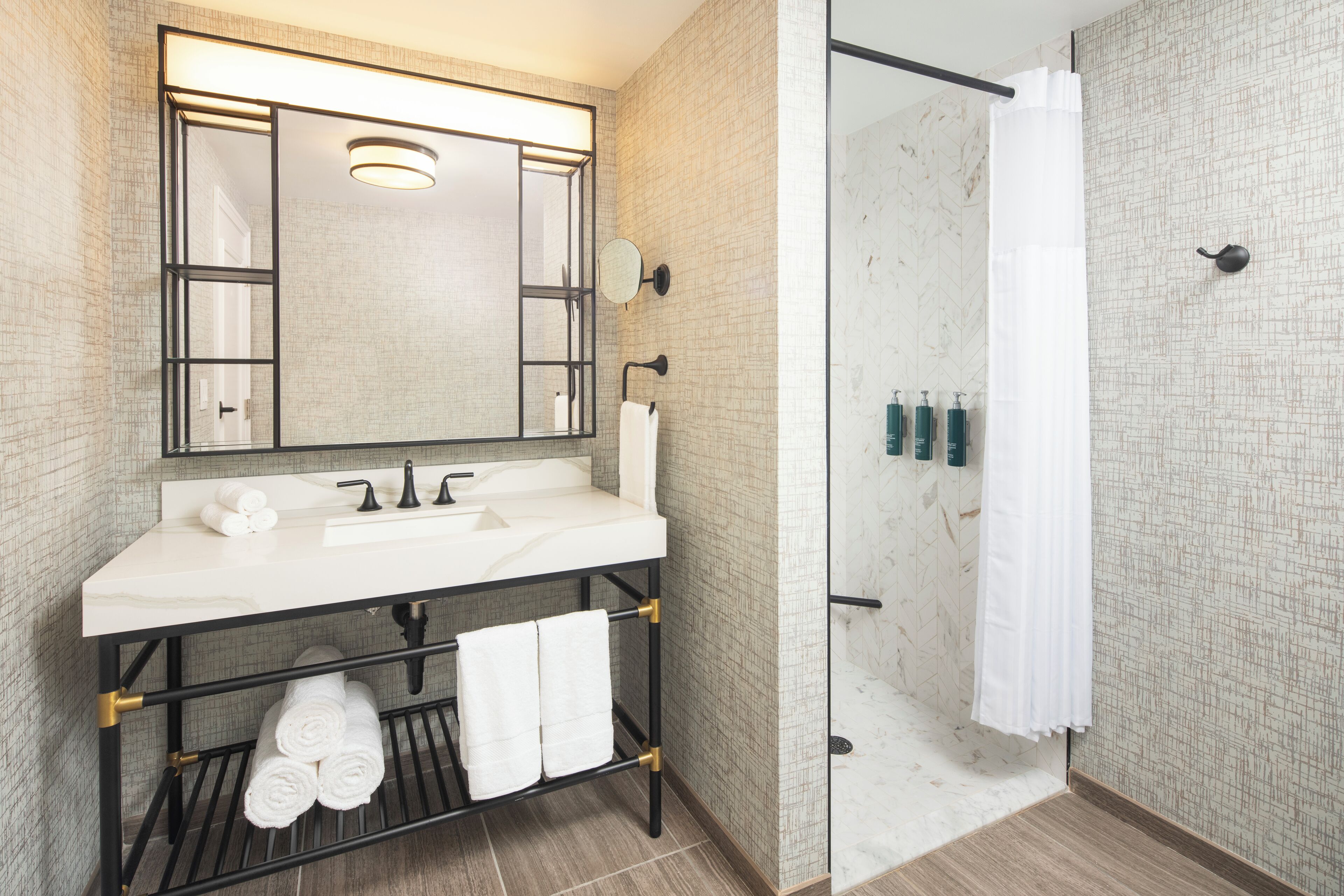 Un baño moderno con un espejo grande, un lavabo blanco y una cabina de ducha de vidrio.