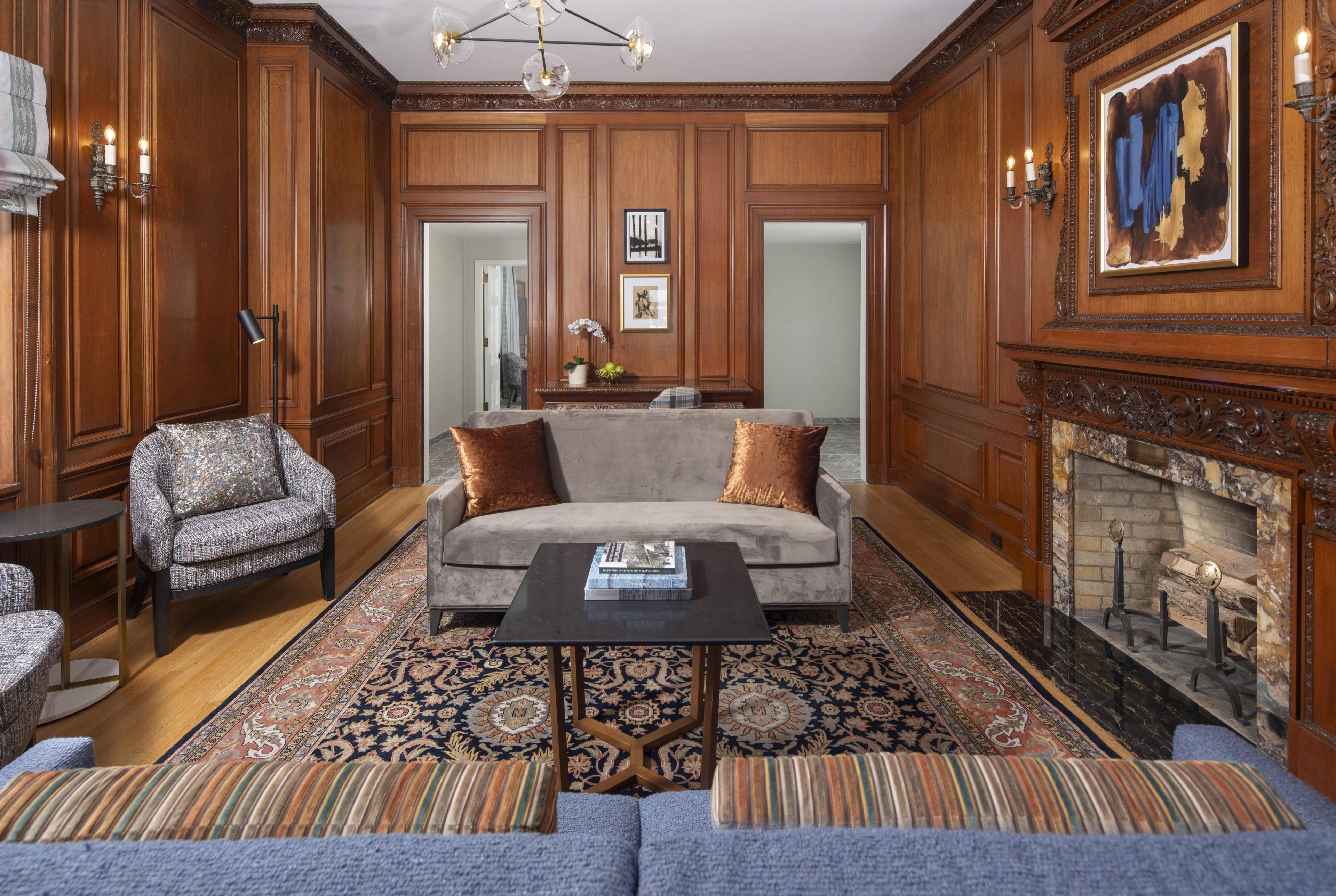 A spacious living room with a grey sofa, patterned armchairs, a coffee table, and a fireplace.