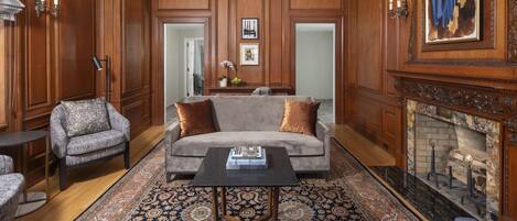 A spacious living room with a grey sofa, patterned armchairs, a coffee table, and a fireplace.