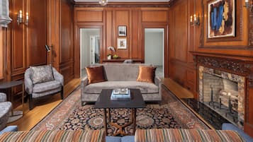 A traditional living room with a fireplace, a sofa, a coffee table, and patterned rugs.